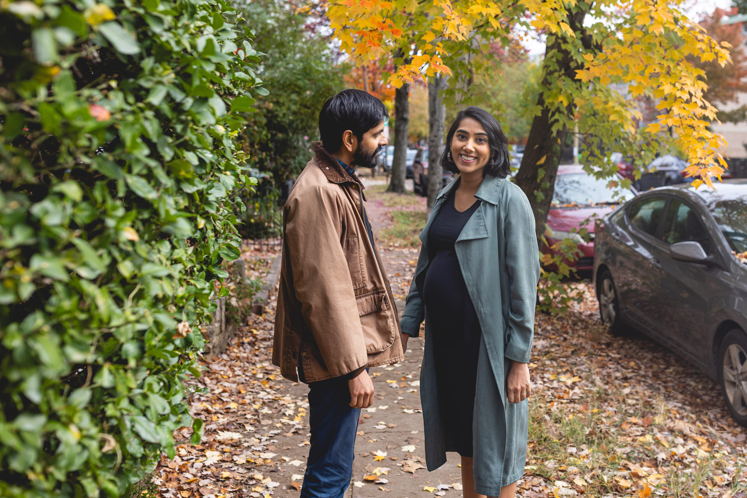 pregnant woman on sidewalk in fall with partner